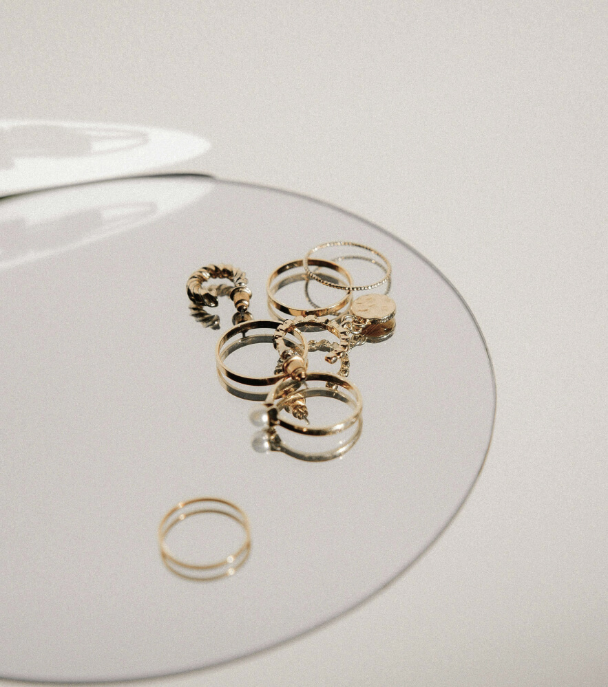 Gold rings and charms on a round mirror