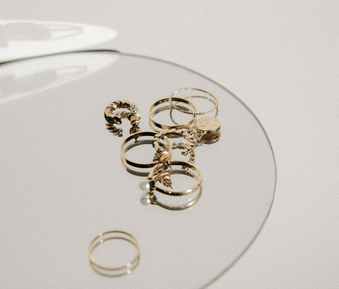 Set of fine gold stacking rings arranged on a mirrored tray