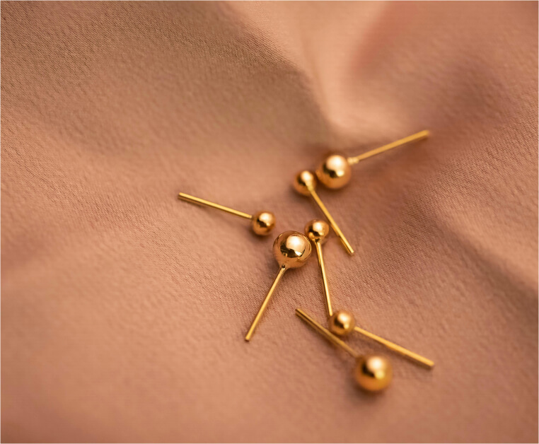 Polished gold ball stud earrings on blush silk