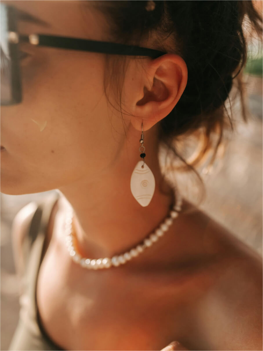 Carved white shell drop earring worn with a freshwater pearl choker